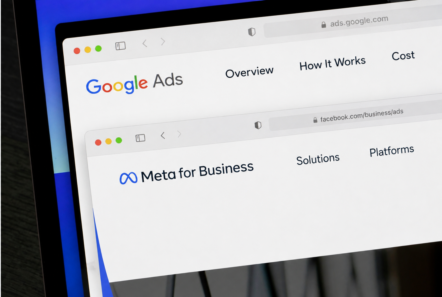 Angled close-up of a computer screen displaying overlapping Google Ads and Meta for Business browser windows.